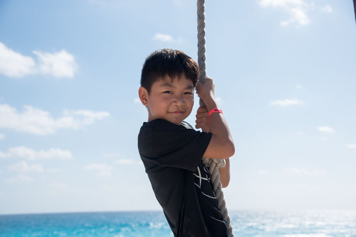 Eric's son climbing a rope with the beautiful beach as background