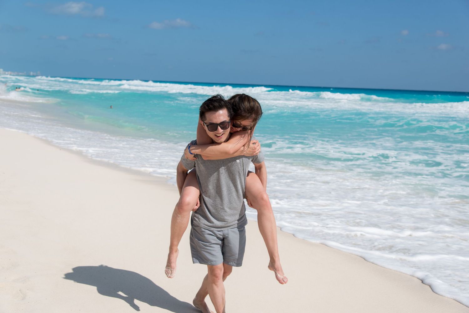 Eric giving his wife a piggyback ride along the shoreline at Playa Delfines in Cancun