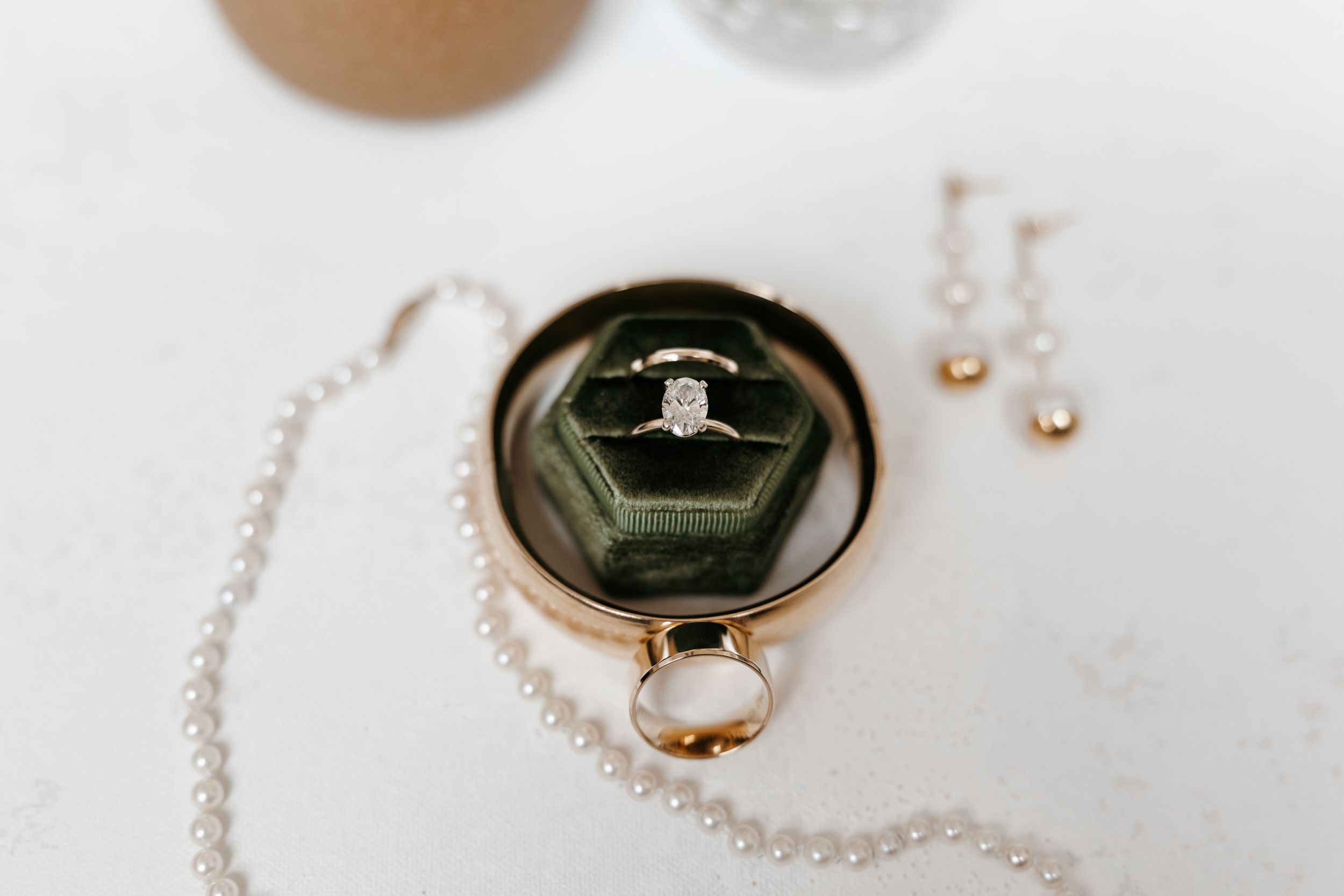Wedding ring detail shot reflected in a vintage mirror with pearl jewelry.