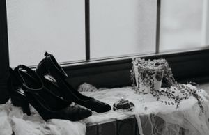Wedding accessories including shoes and jewelry arranged on a light surface.