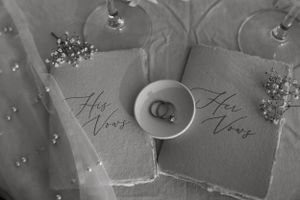 Black and white overhead shot of His and Hers vow books with wedding rings.