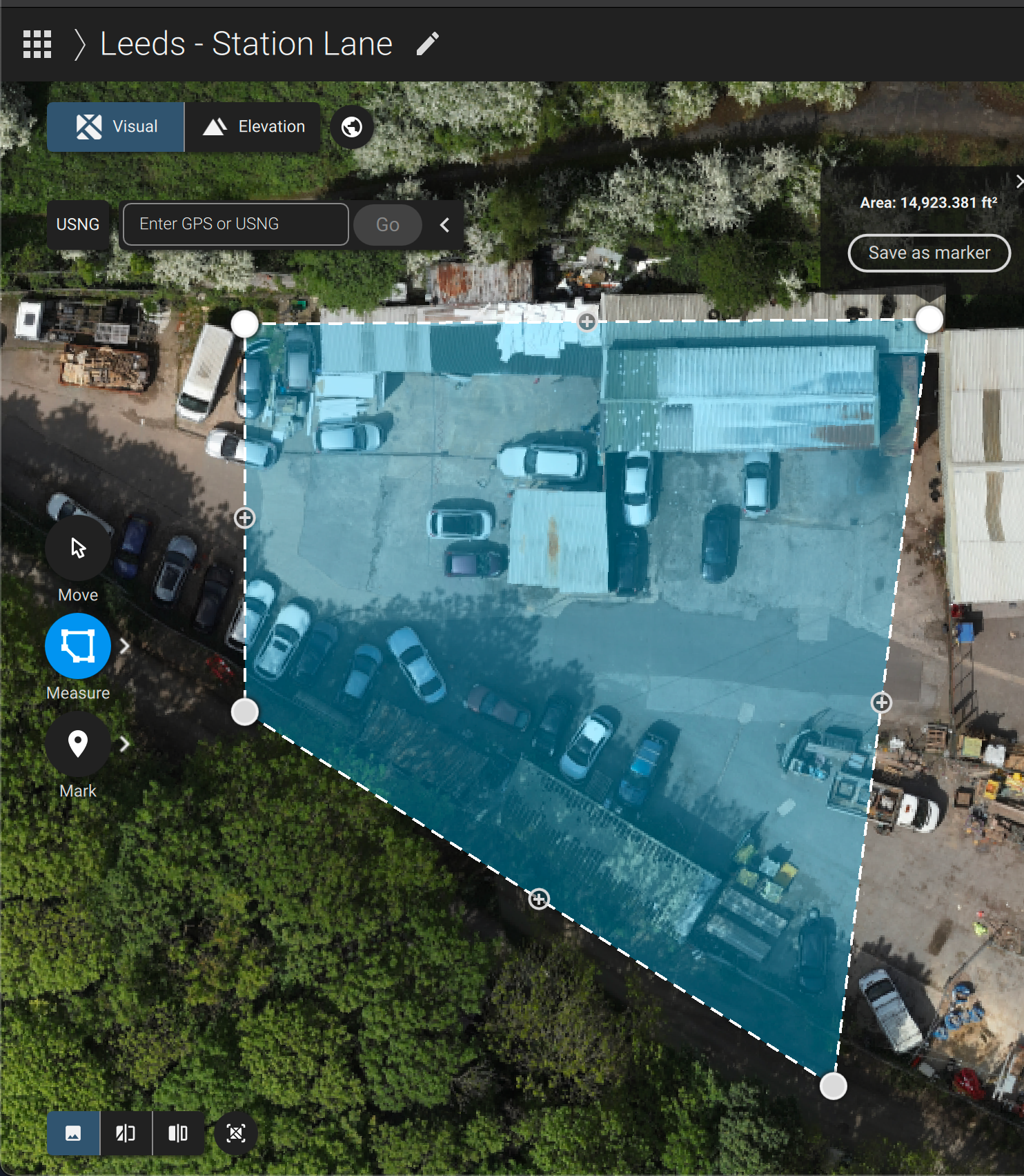 Aerial map view of a parking lot area highlighted in blue overlay showing parked vehicles and surrounding vegetation.
