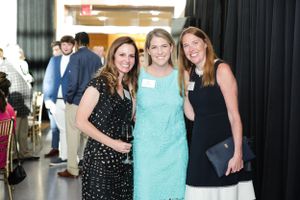 Three attendees pose together at an indoor social gathering.