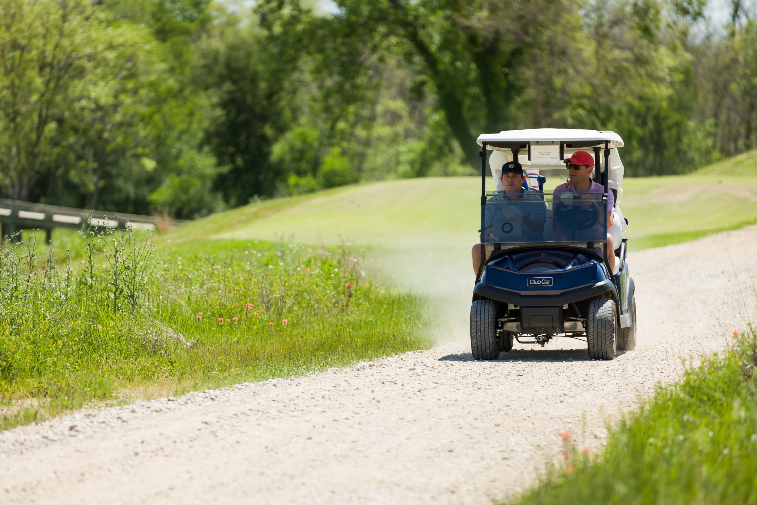 Golf carts driving along a winding path through lush green landscape.