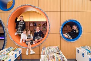 Children sit inside colorful circular wall installations in library setting.