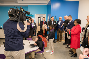 Camera operator films group meeting with media coverage in office setting.