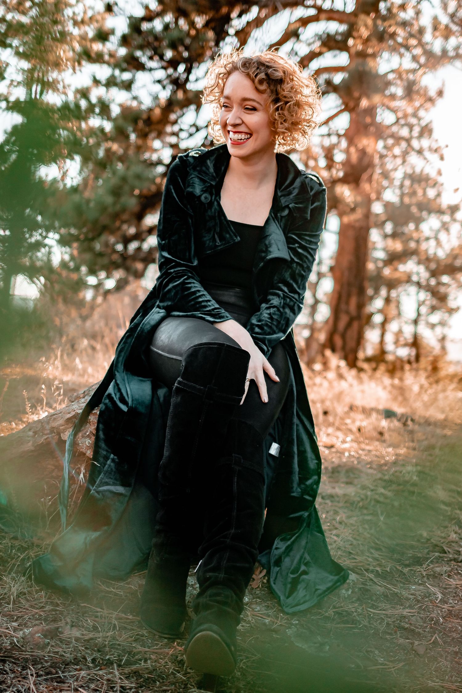 Person in emerald velvet dress twirling outdoors among autumn trees. Denver Portrait Photography.
