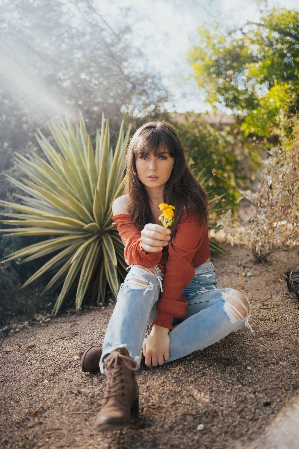 A desert garden photoshoot featuring someone in casual wear posing near yucca plants.