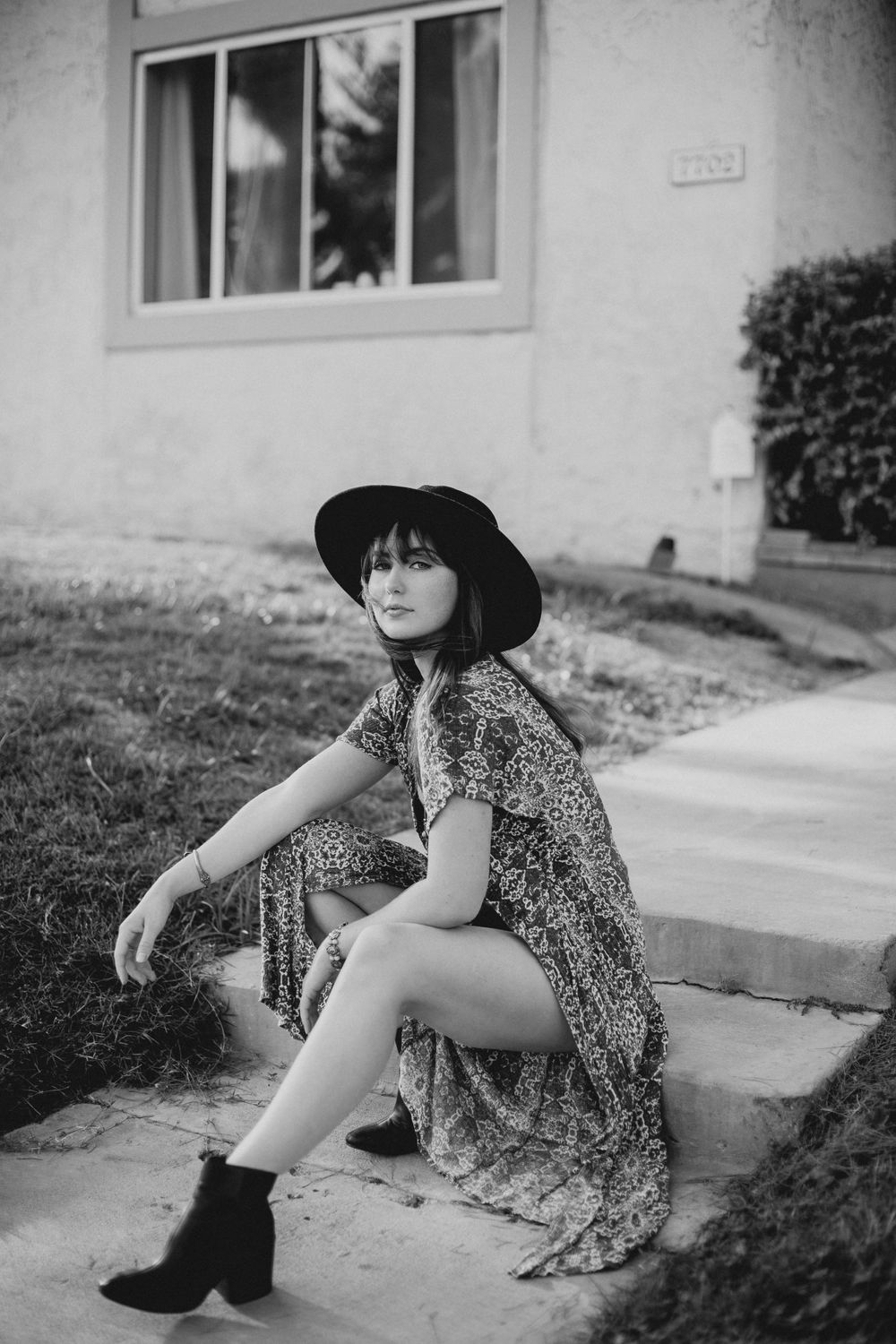 Black and white portrait series showing a floral dress and hat against architectural backdrop.