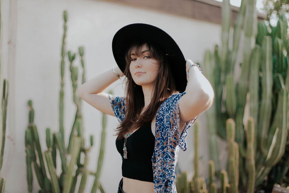 Artistic portrait series against a white wall with desert landscaping and cacti.