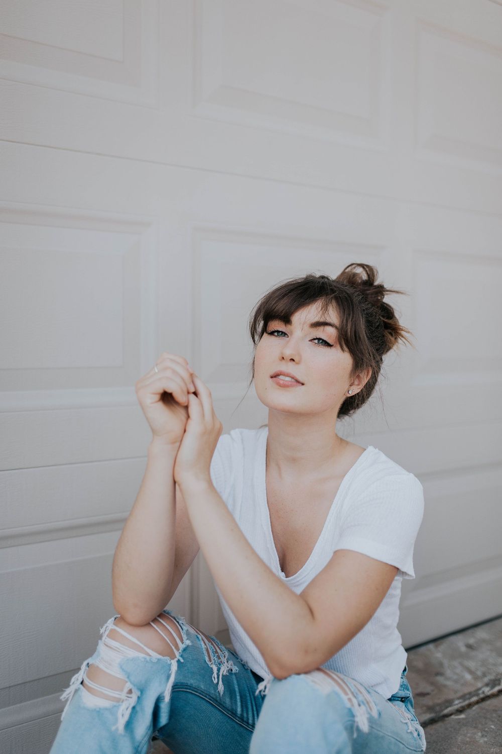 Relaxed portrait session against white background in classic white tee and distressed denim.