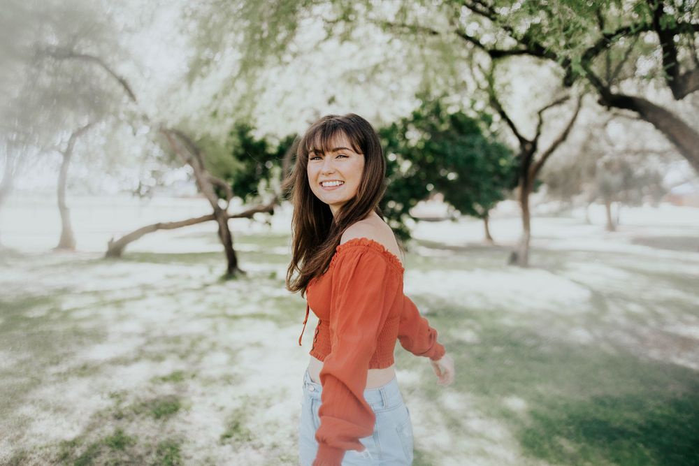Outdoor portrait in coral colored top against natural green background.