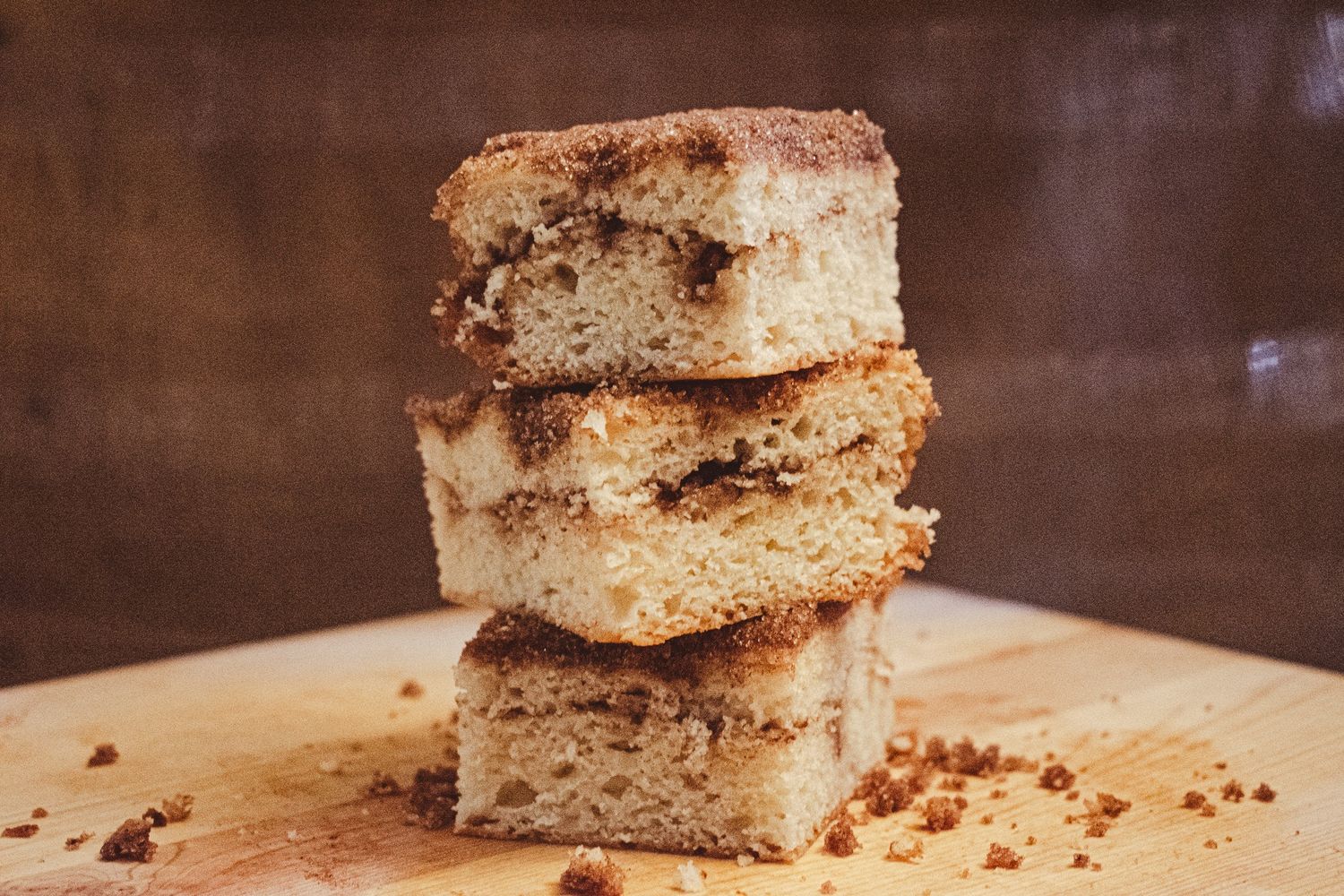 Three stacked slices of cinnamon coffee cake on a rustic wooden surface.