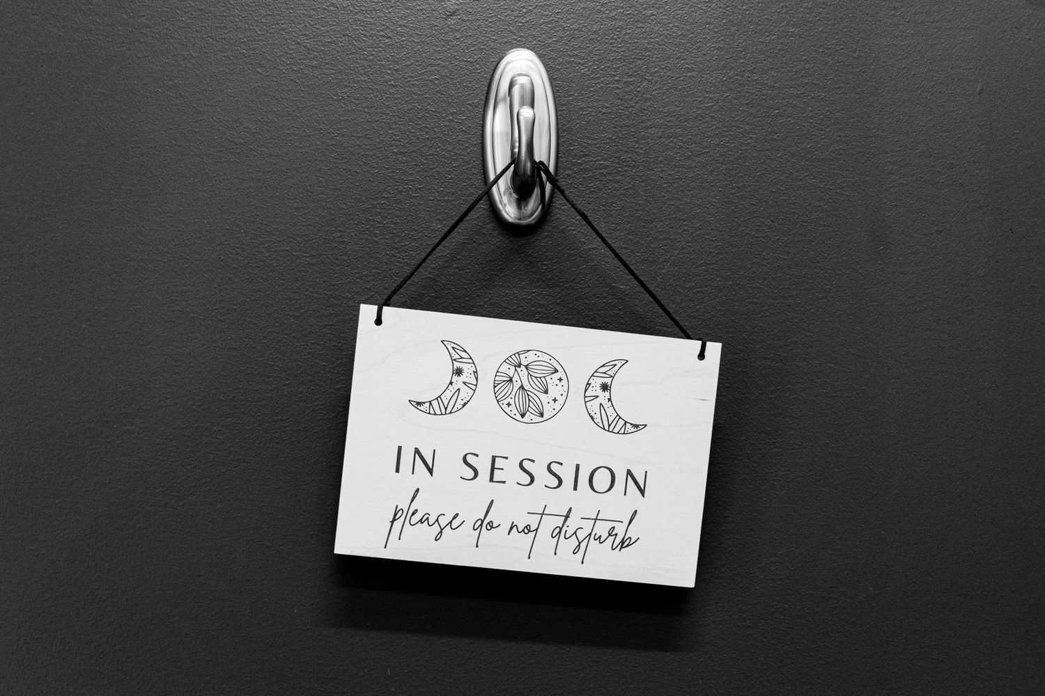 A black and white sign with moon phases and 'In Session Please Do Not Disturb' text hangs on a wall.