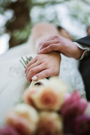 Detalle de manos y ramo en sesión de pareja de novios el día de su boda