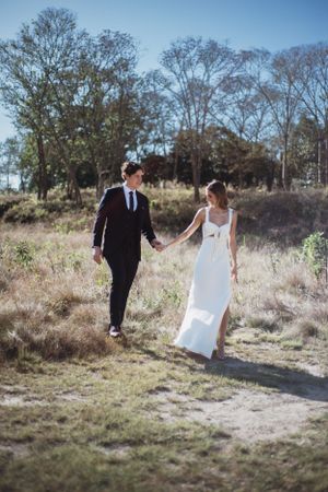 Novios corriendo por el campo en sesión de pareja artísitca