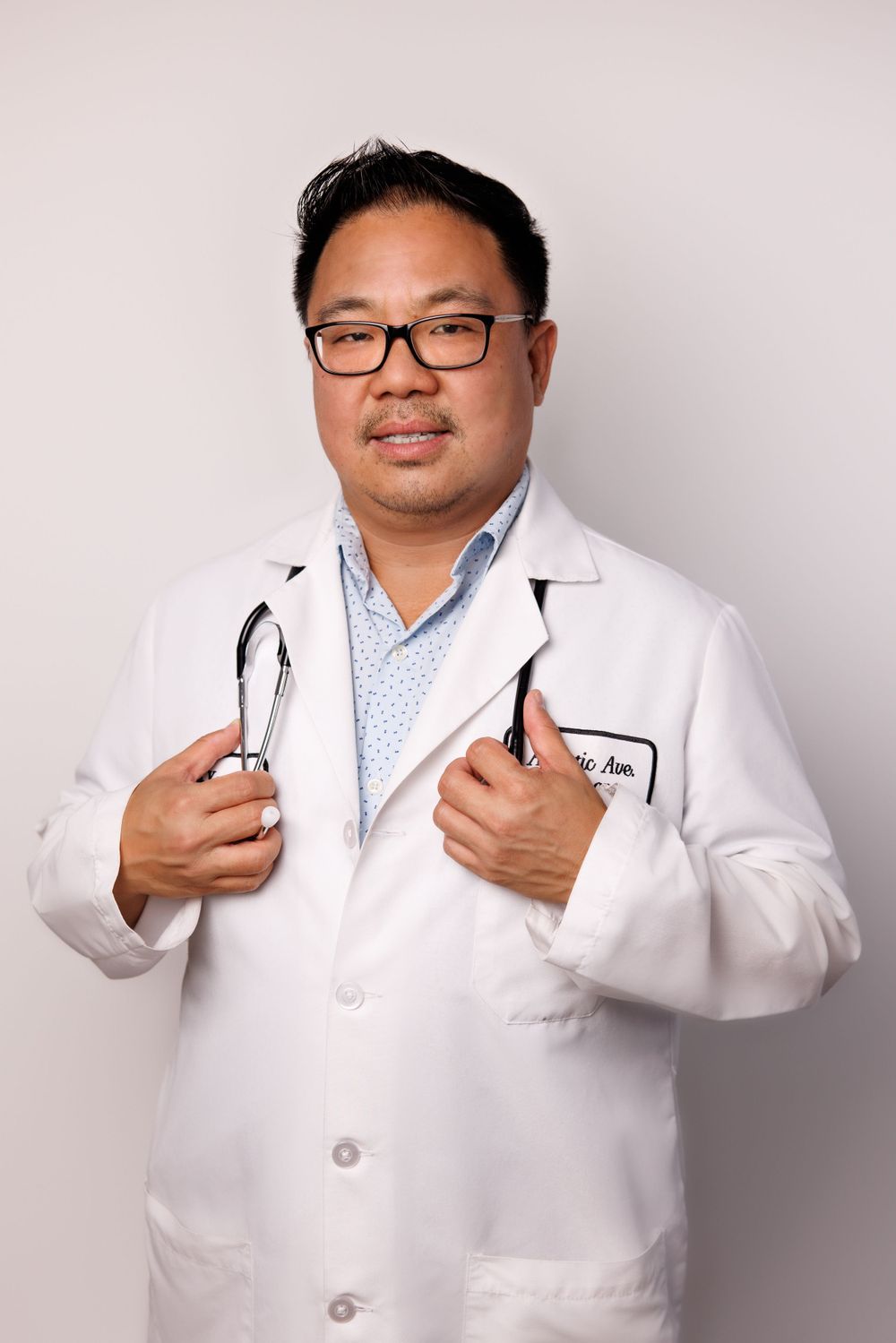 Professional headshots of medical practitioner in white coat against grey background.