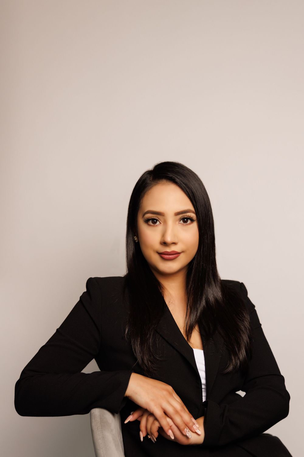 Professional portrait of person in black blazer seated with confident pose.