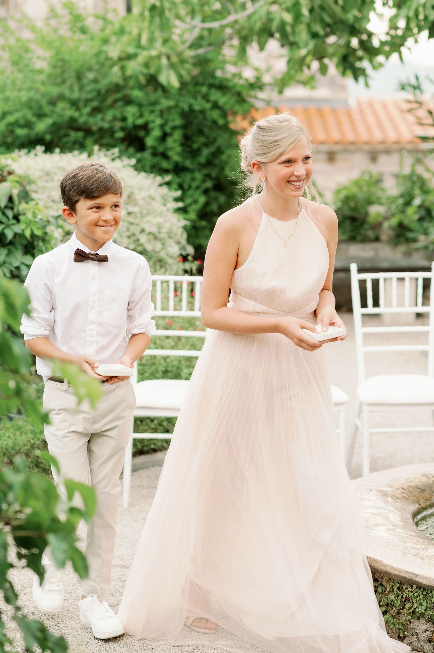 Wedding attendants in formal attire standing in a lush garden setting.