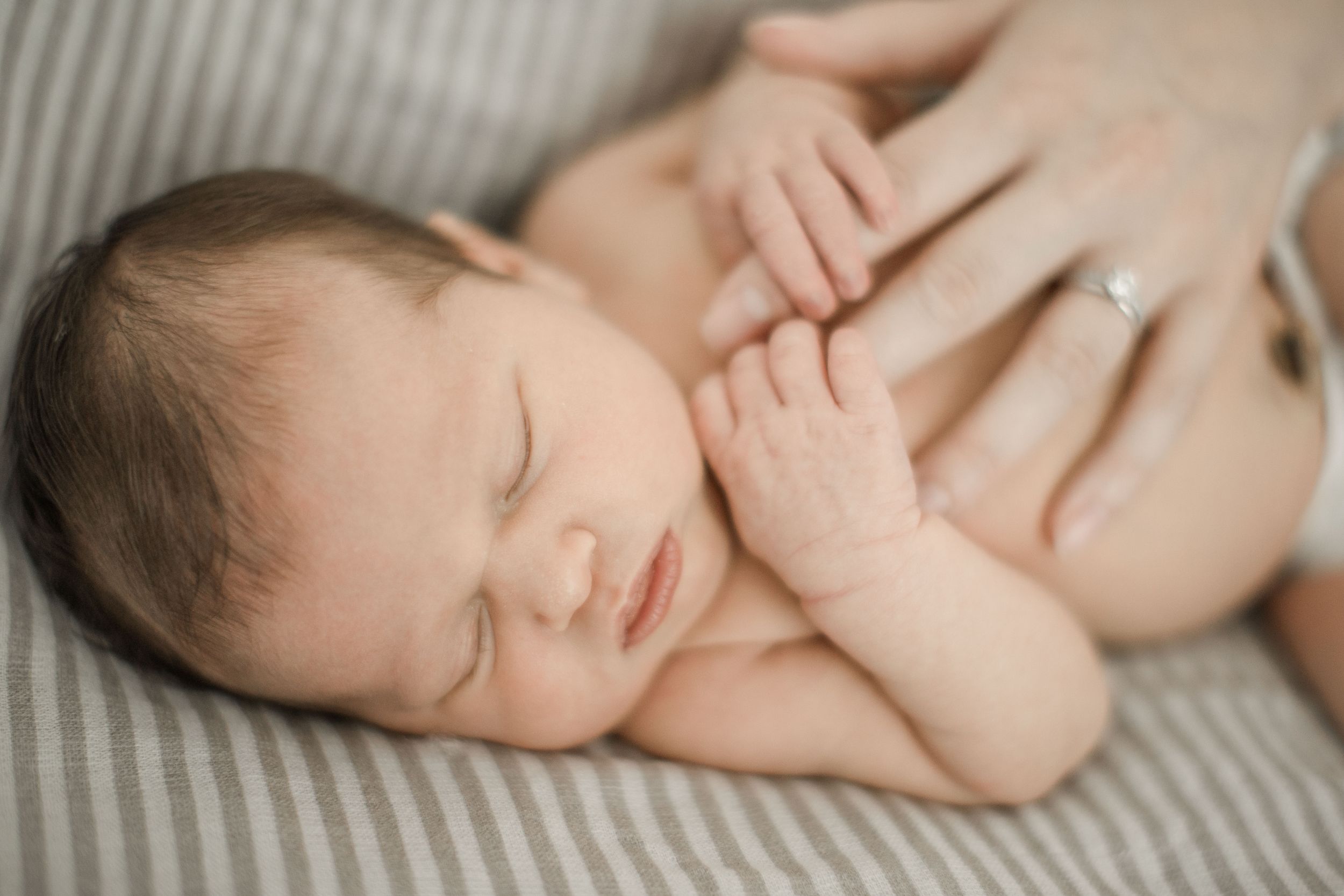 Portrait of a newborn holding on to her mothers fingers
