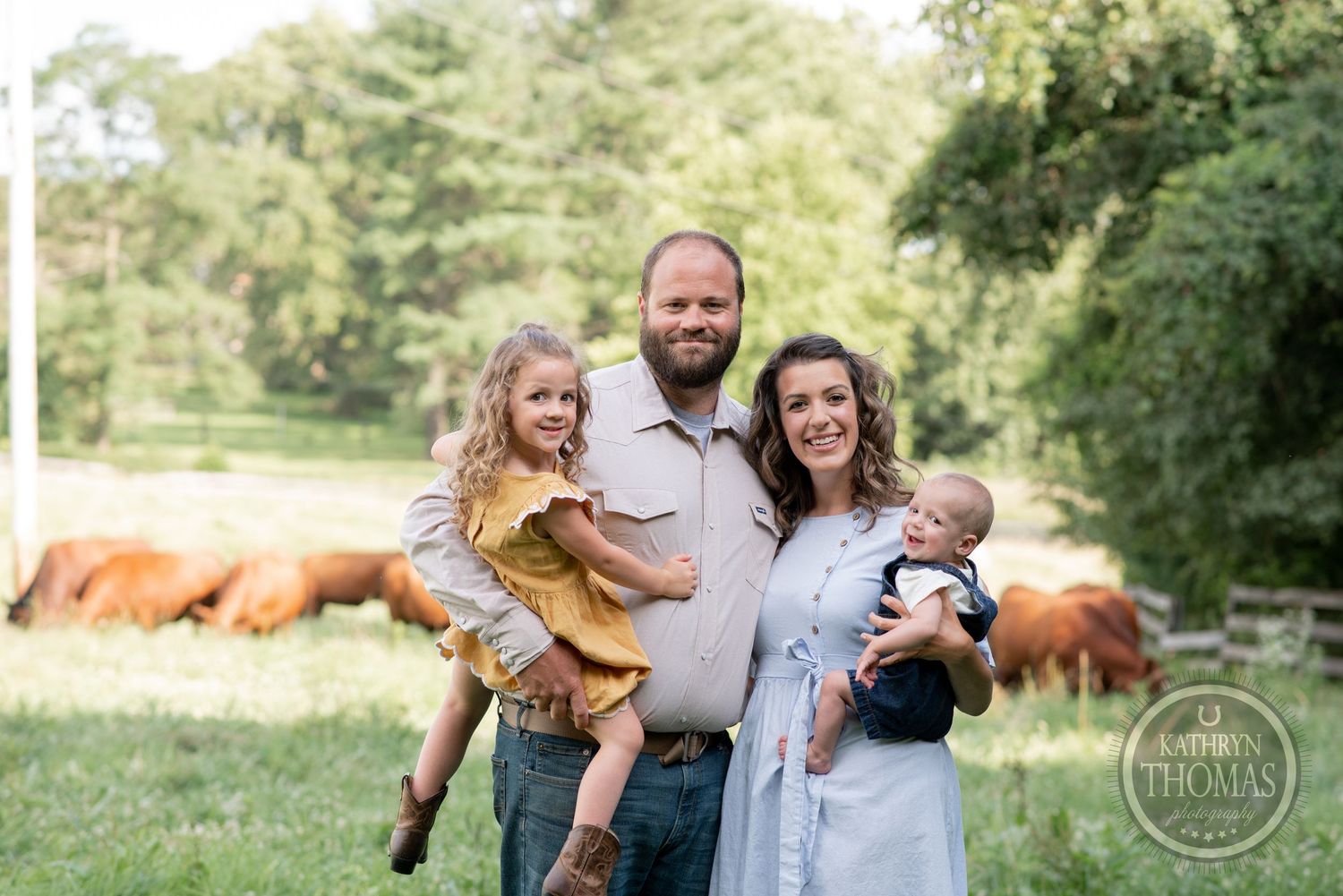 Family portrait with cattle grazing in the background on their farm.