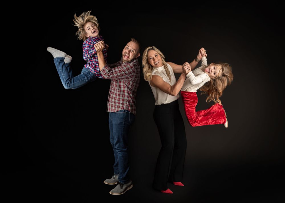 Dynamic studio portrait with people in casual wear jumping against black background.