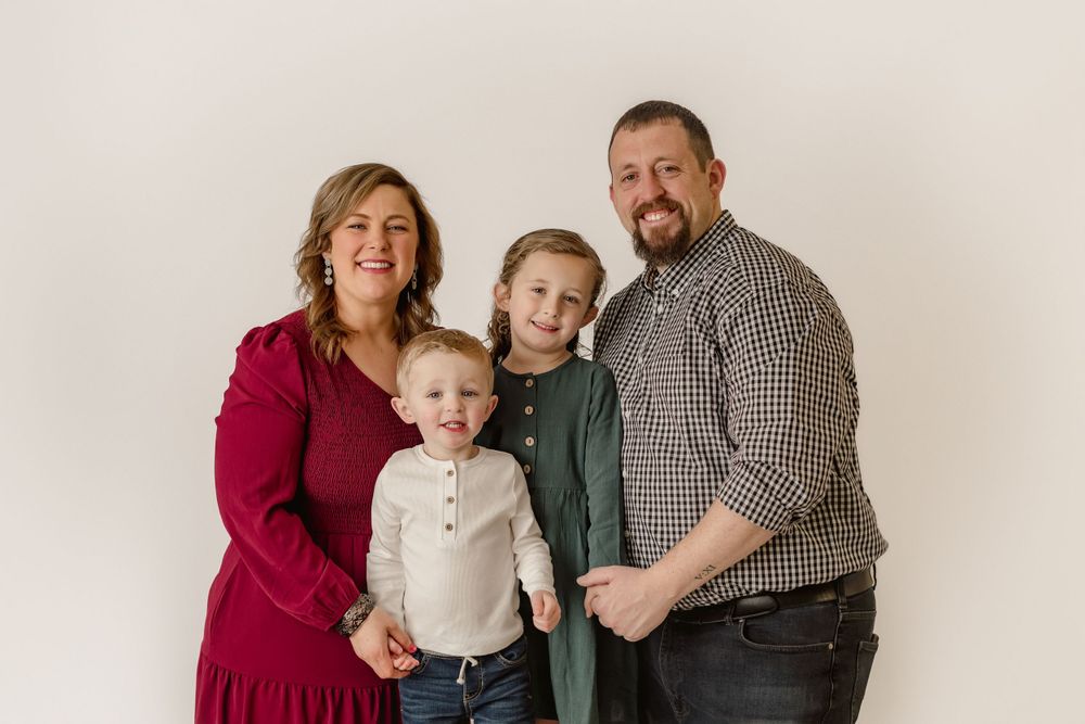 Studio portrait of a family of four against white backdrop.