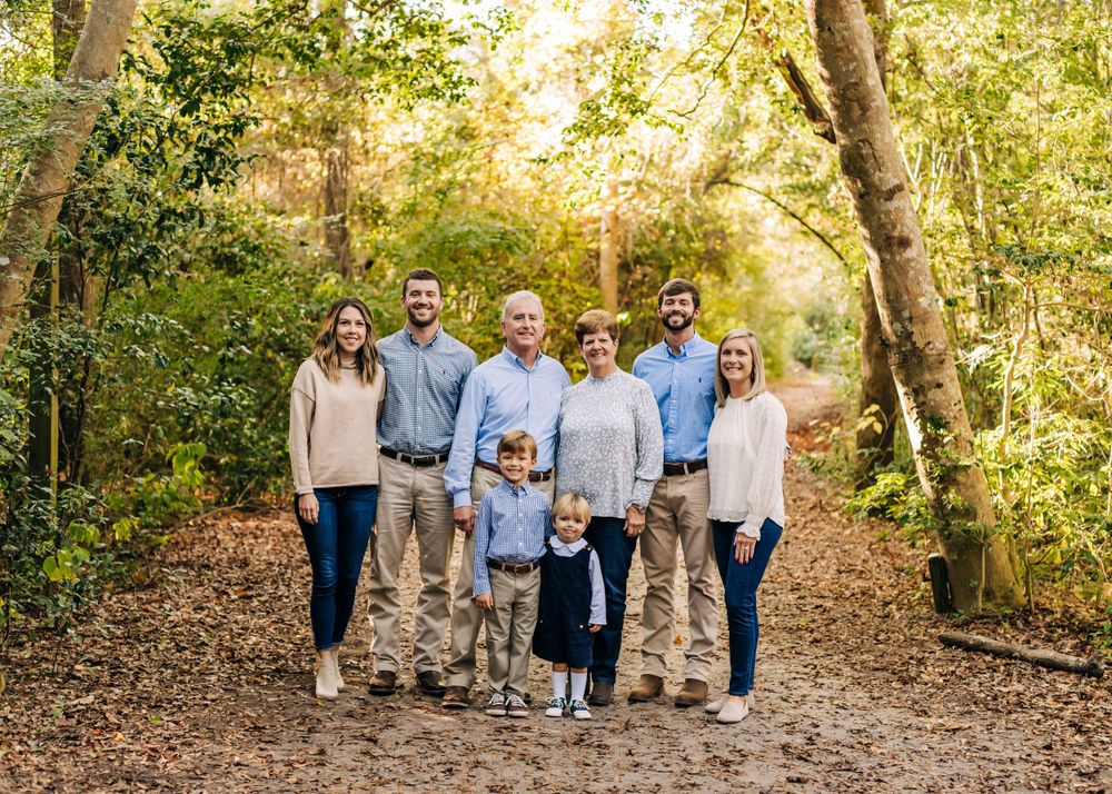 Extended family walking together on a wooded trail during golden hour.