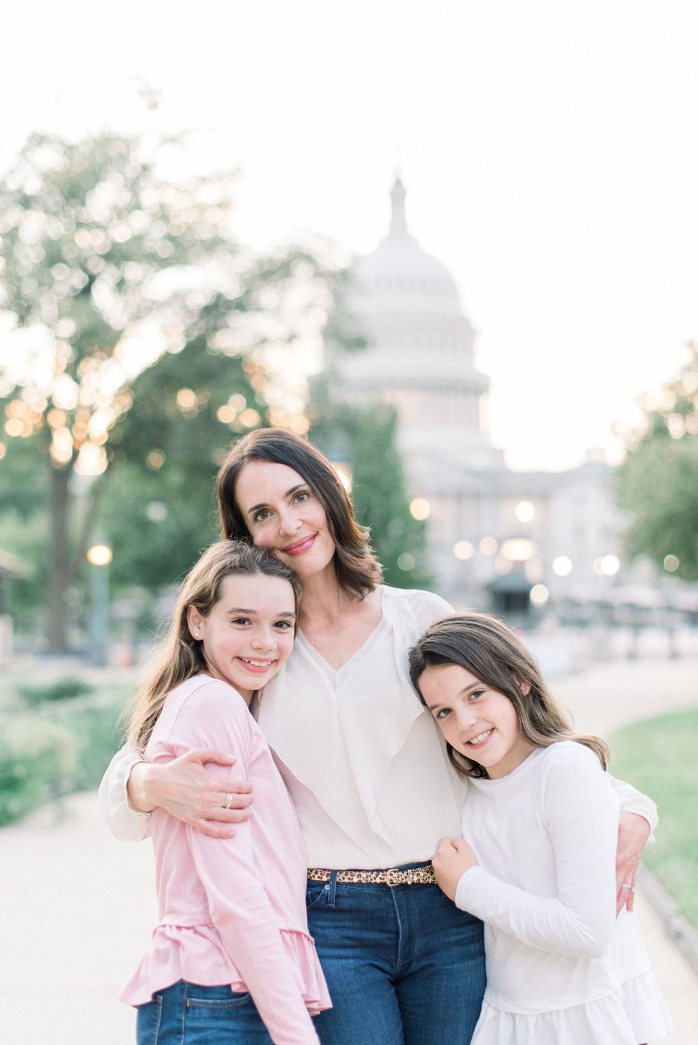 Three people pose for a portrait on the National Mall with the US Capitol building visible in the evening light.
