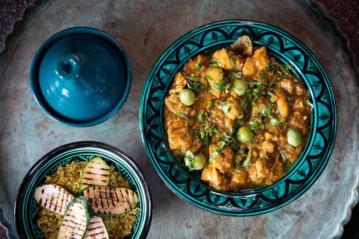 Middle Eastern dish served in decorative turquoise plate alongside grilled bread from a product photoshoot.