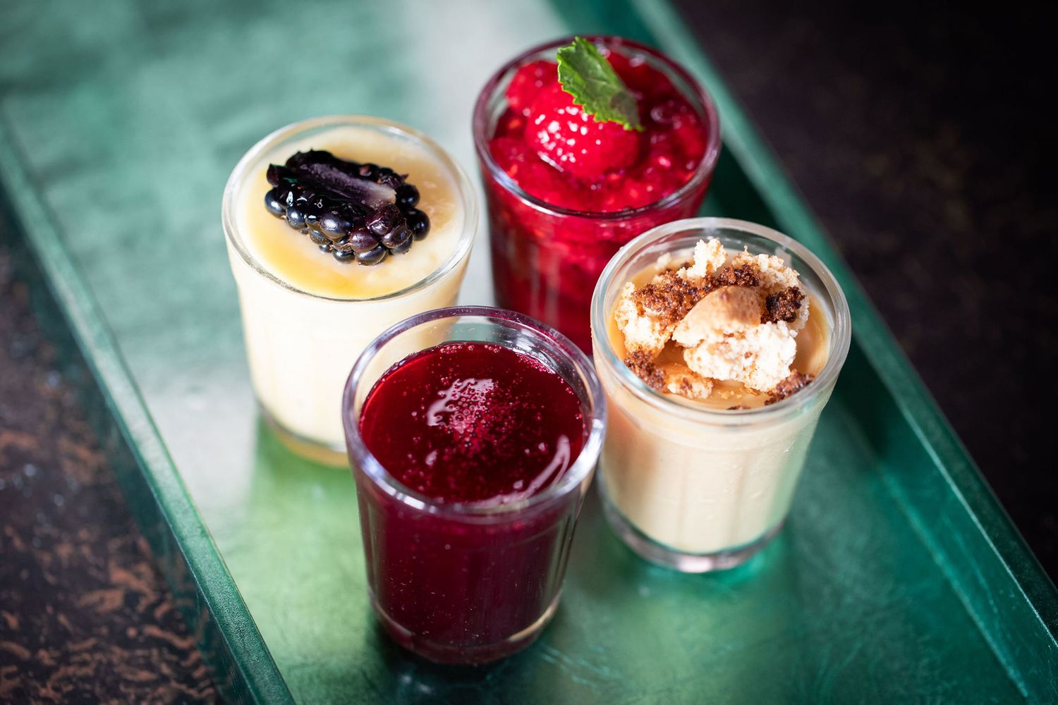 Four dessert jars featuring various flavors including berry compote and cream from a product photoshoot.