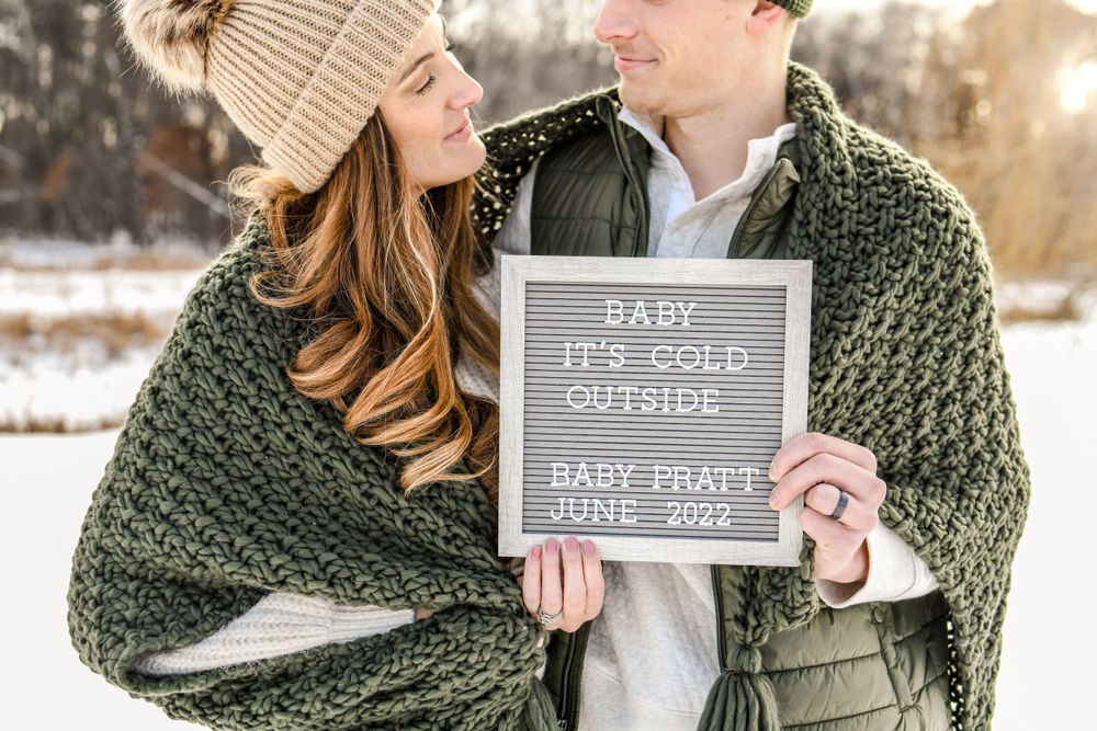 Winter pregnancy announcement photoshoot with letter board in snow.