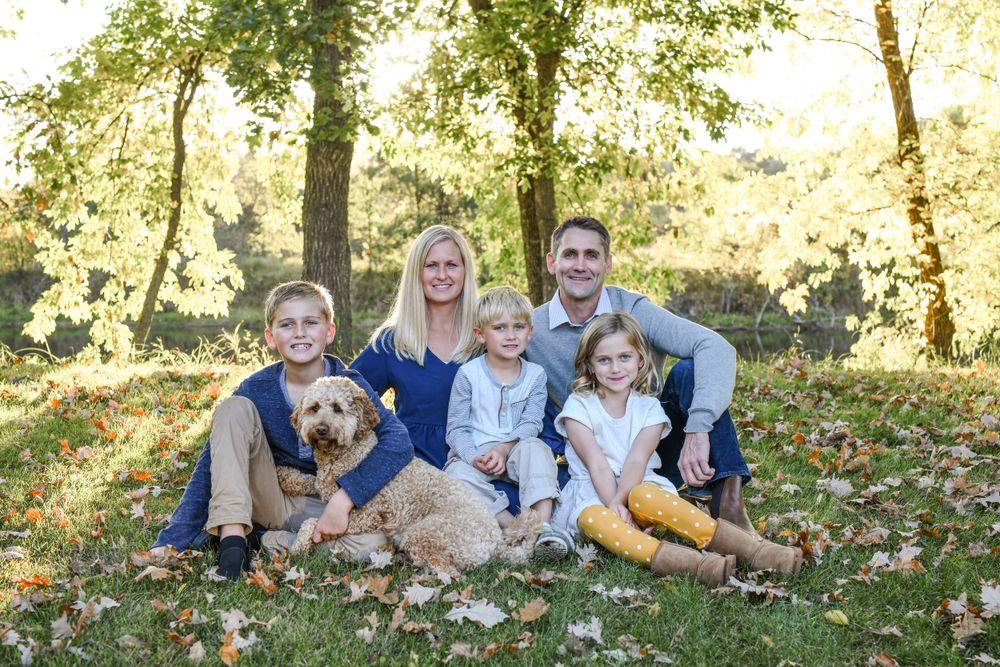 Family and golden retriever enjoying a relaxed outdoor photoshoot on a blanket in autumn.