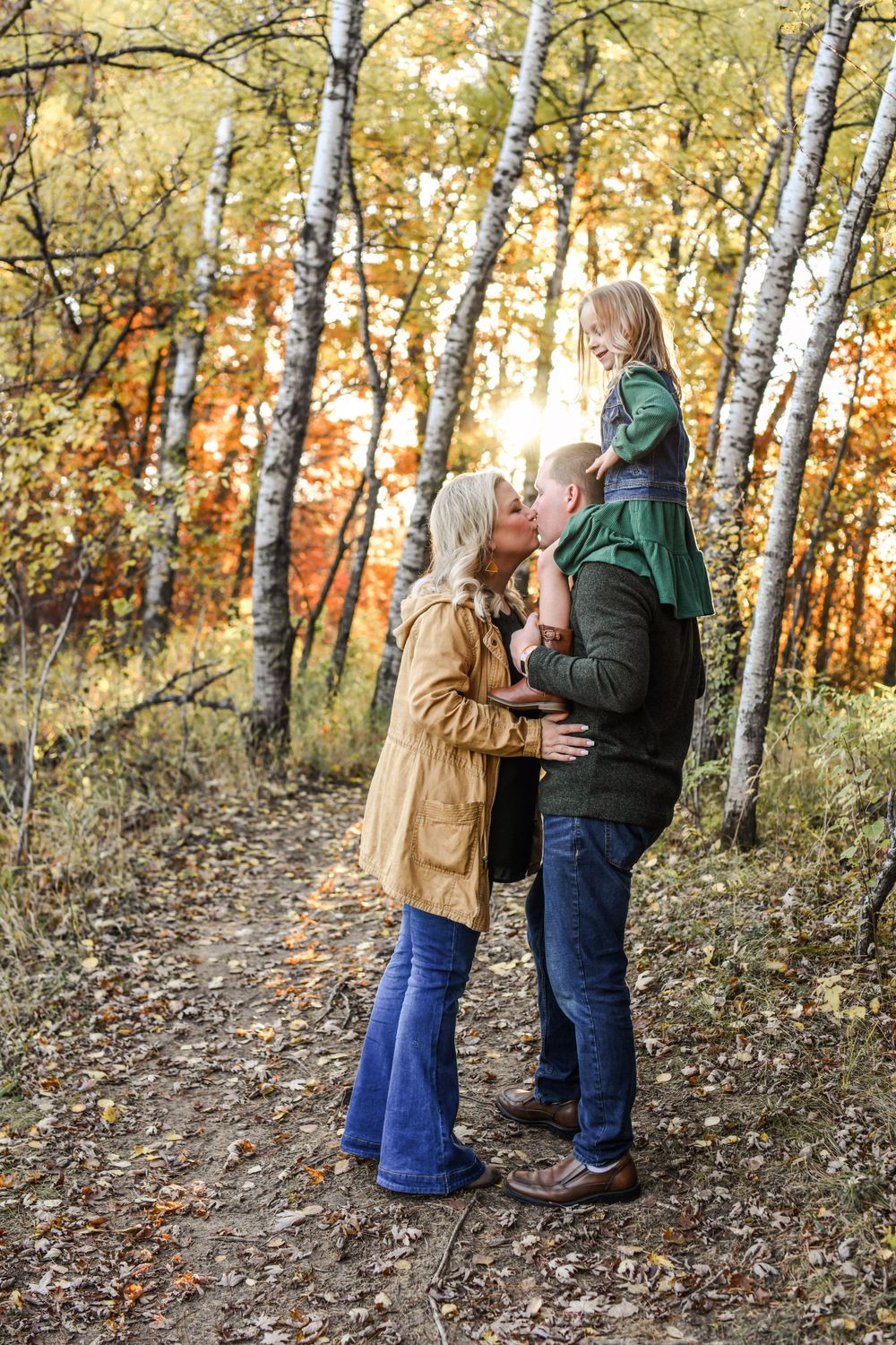 Couple sharing tender moment among autumn birch trees at sunset.