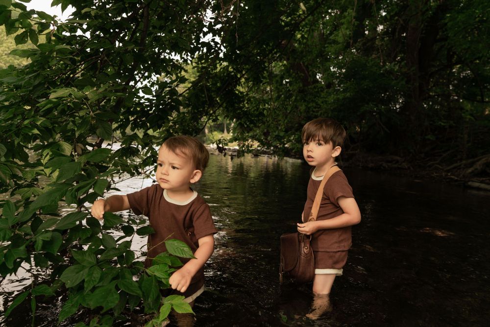 brothers look out at water from the shallows