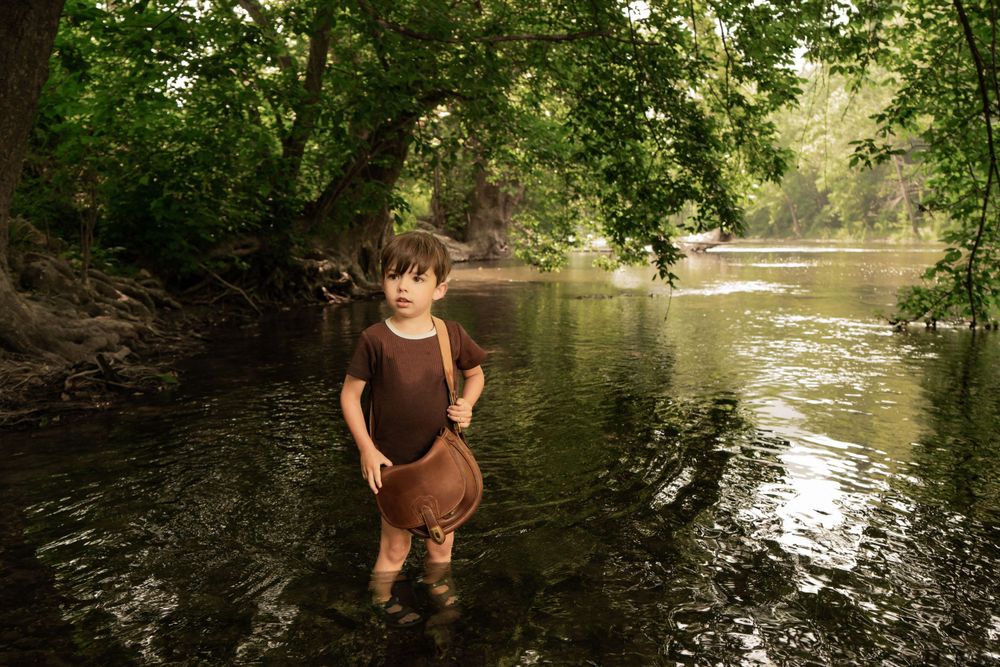 boy stands in river looking downstream