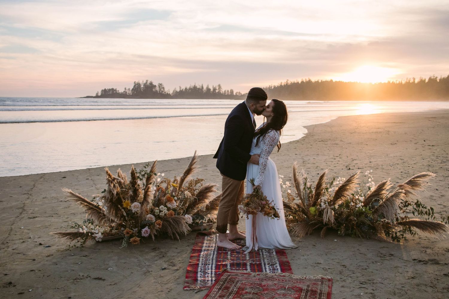 Bride and groom kissing in front of sunset on the beach during their Tofino, British Columbia Beach Elopement