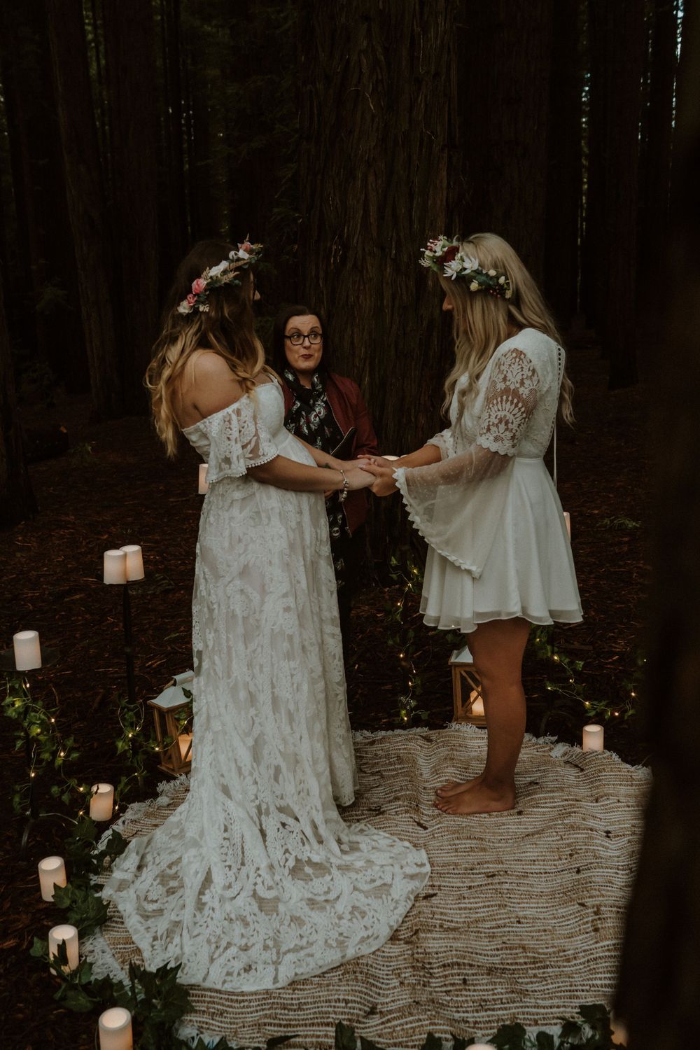 People in white lace dresses dancing on a decorated forest floor.