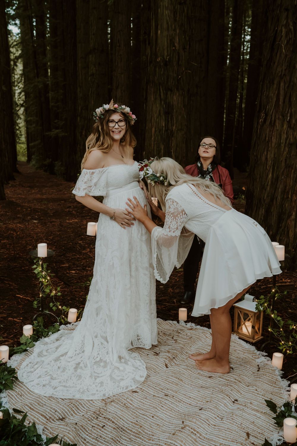 People in white dresses celebrating and dancing together in a decorated forest setting.