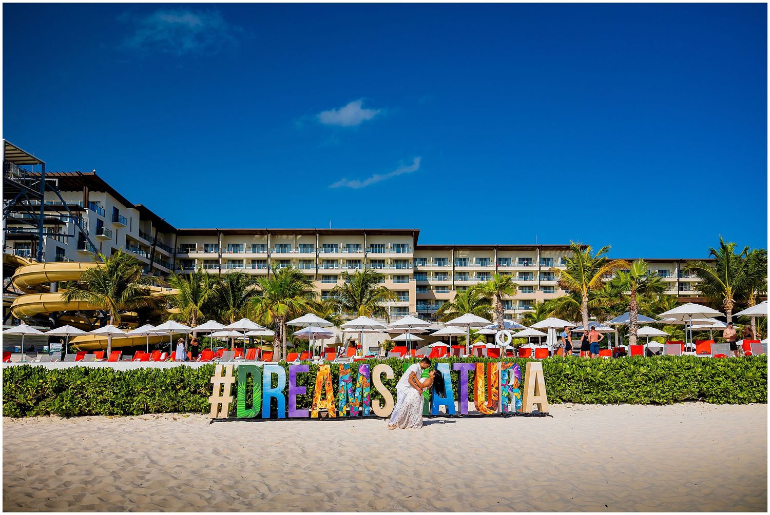 Beachside resort hotel with colorful 'DREAMS TULUM' sign decorating the sandy shore.