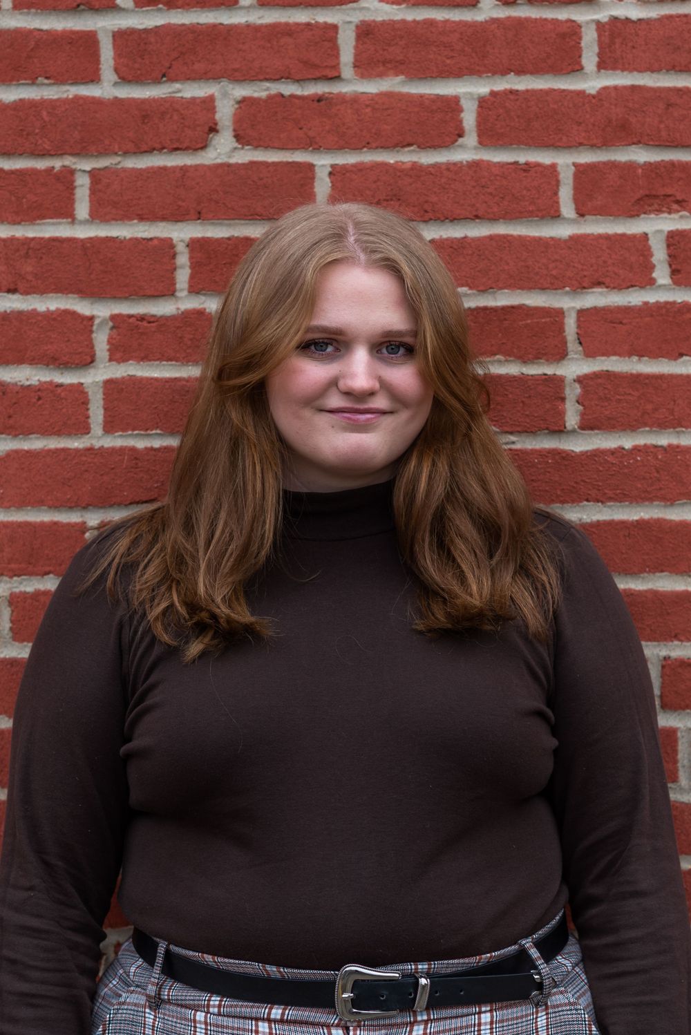 Casual portrait against red brick wall in brown turtleneck.