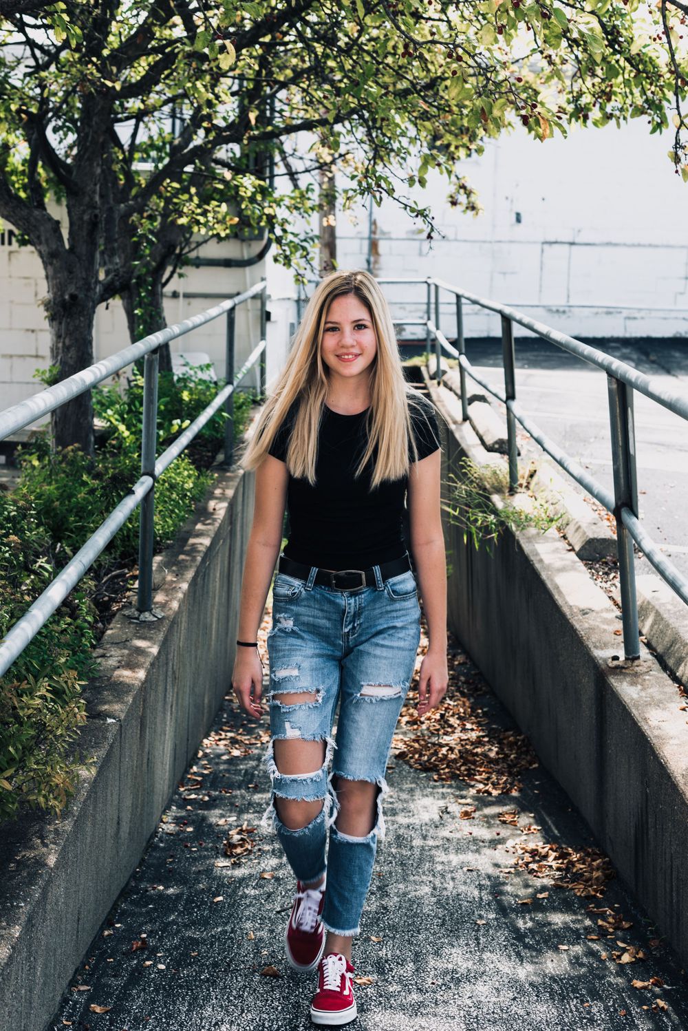 Outdoor portrait session on wooden walkway with distressed denim and casual style.