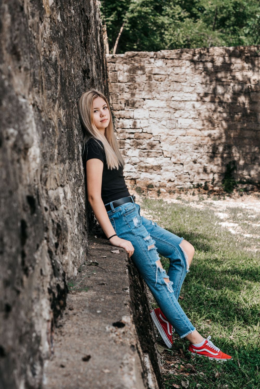 Distressed denim and casual wear styled against rustic stone wall in outdoor setting.