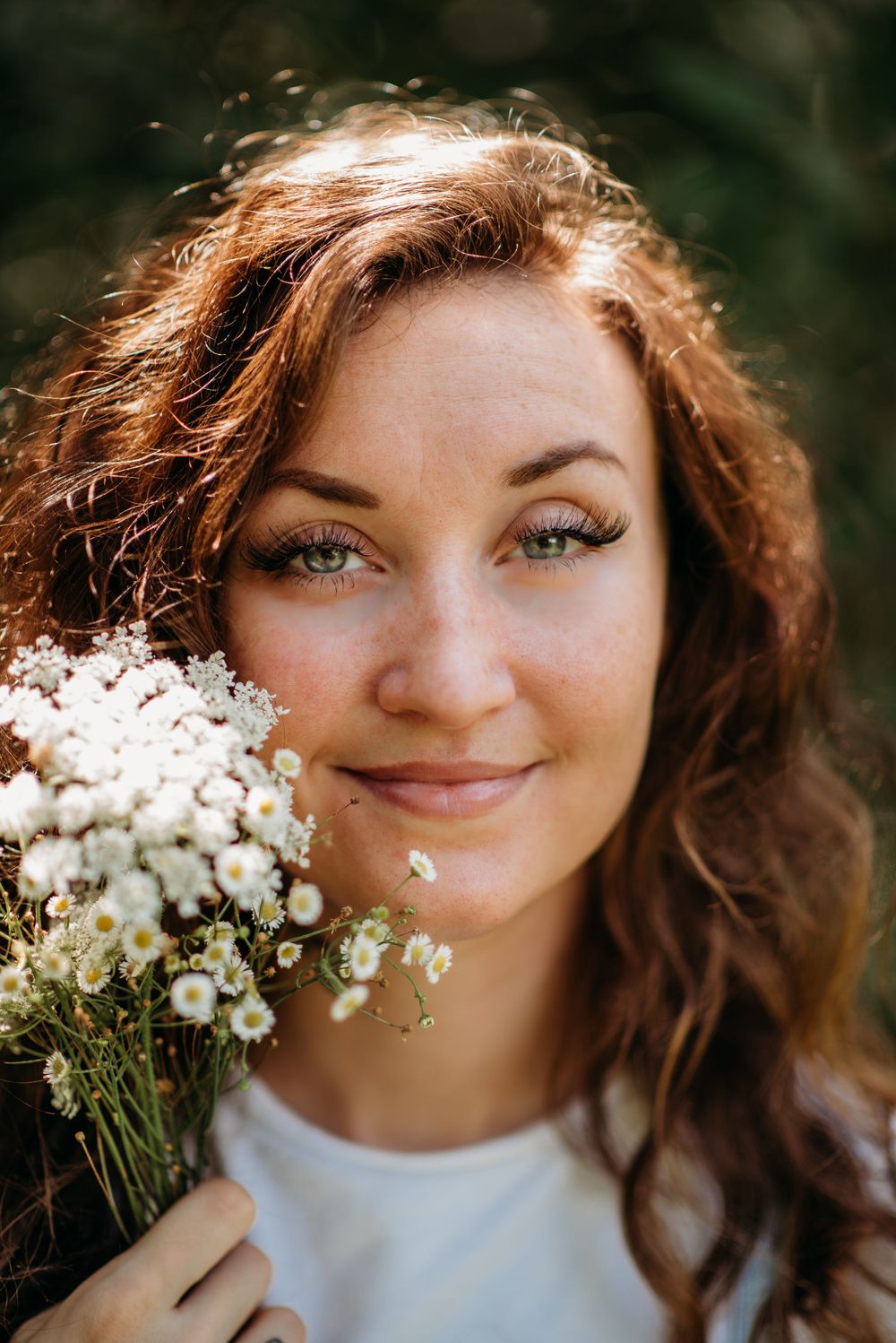 Portrait with white flowers against natural outdoor background featuring soft lighting.