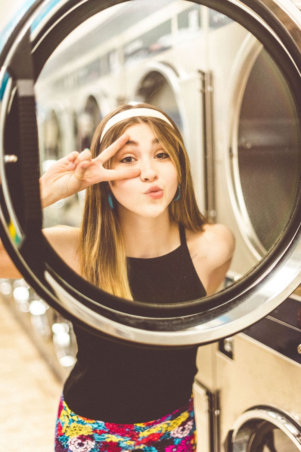 Creative portrait through a washing machine door window at a laundromat.