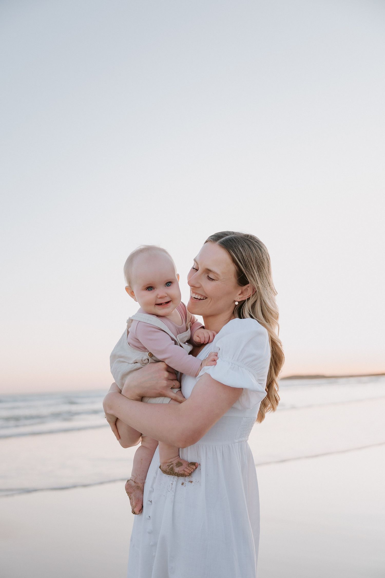 A tender moment between two figures on a sunny beach with soft lighting.