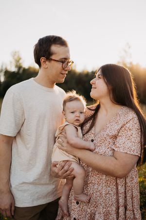 Intimate family portrait at sunset with warm golden light filtering through trees.