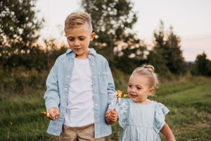 Two children in coordinating outfits standing together in an evening field.