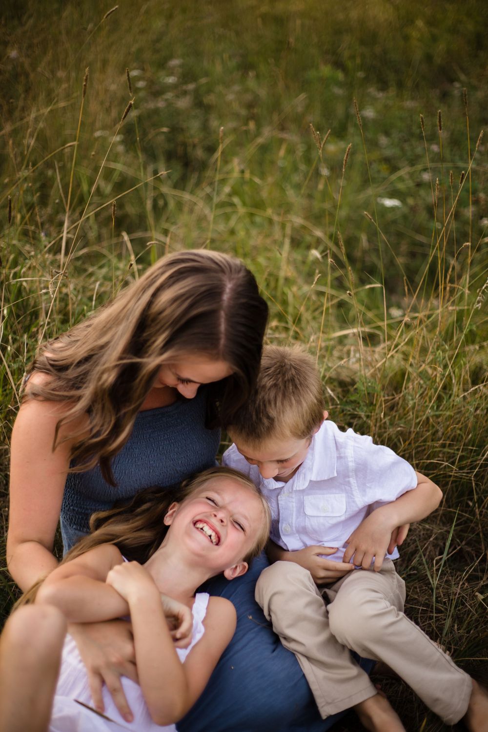 Candid family moment showing playful interaction in a grassy outdoor setting.