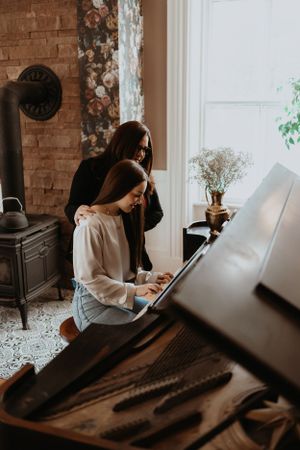 A series of moody photos showing someone playing piano in a room with exposed brick walls.